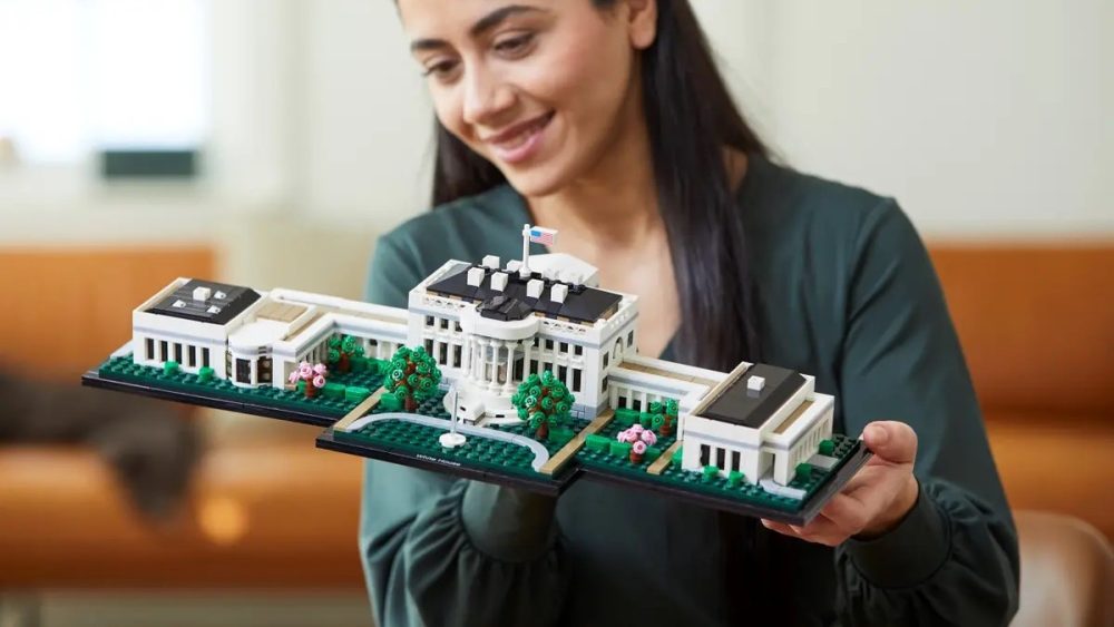 En kvinna håller upp sitt färdiga Lego-bygge föreställande Vita huset.